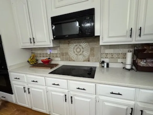 a kitchen with white cabinets and sink