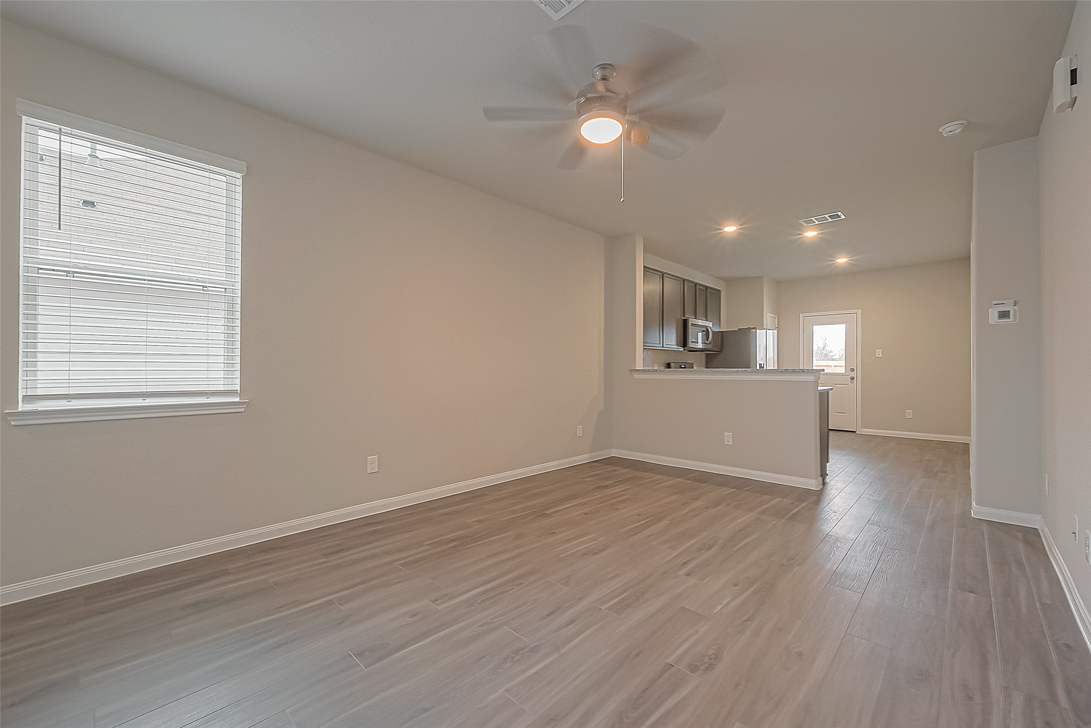 4923 Luke Matthew Drive Rosharon, TX 77583 - Photo 12 of 48 a view of a kitchen and an empty room with wooden floor