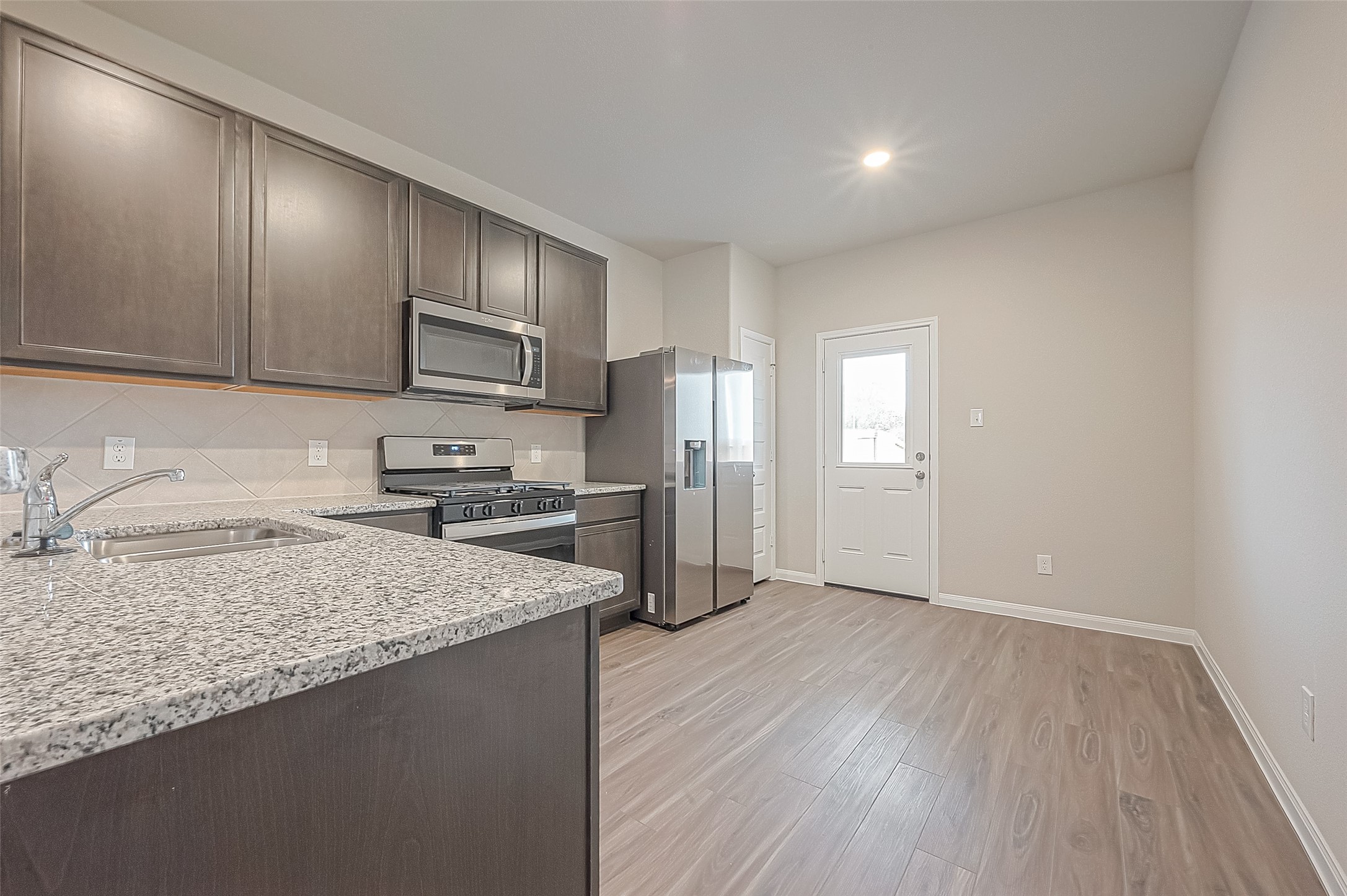4923 Luke Matthew Drive Rosharon, TX 77583 - Photo 15 of 48 a kitchen with granite countertop a refrigerator and wooden floor
