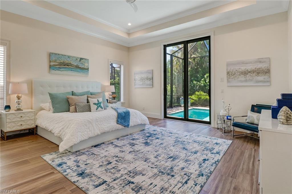 2875 Coco Lakes Drive Naples, FL 34105 - Photo 11 of 27 Bedroom featuring access to exterior, ornamental molding, wood-type flooring, and a tray ceiling