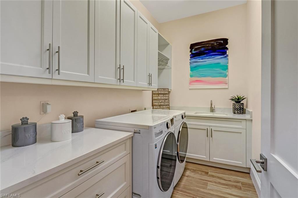 2875 Coco Lakes Drive Naples, FL 34105 - Photo 13 of 27 Washroom with separate washer and dryer, sink, cabinets, and light wood-type flooring