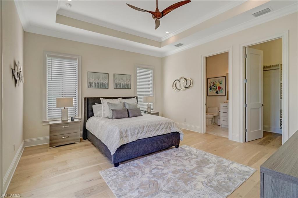 2875 Coco Lakes Drive Naples, FL 34105 - Photo 16 of 27 Bedroom featuring a raised ceiling, connected bathroom, ceiling fan, and light wood-type flooring