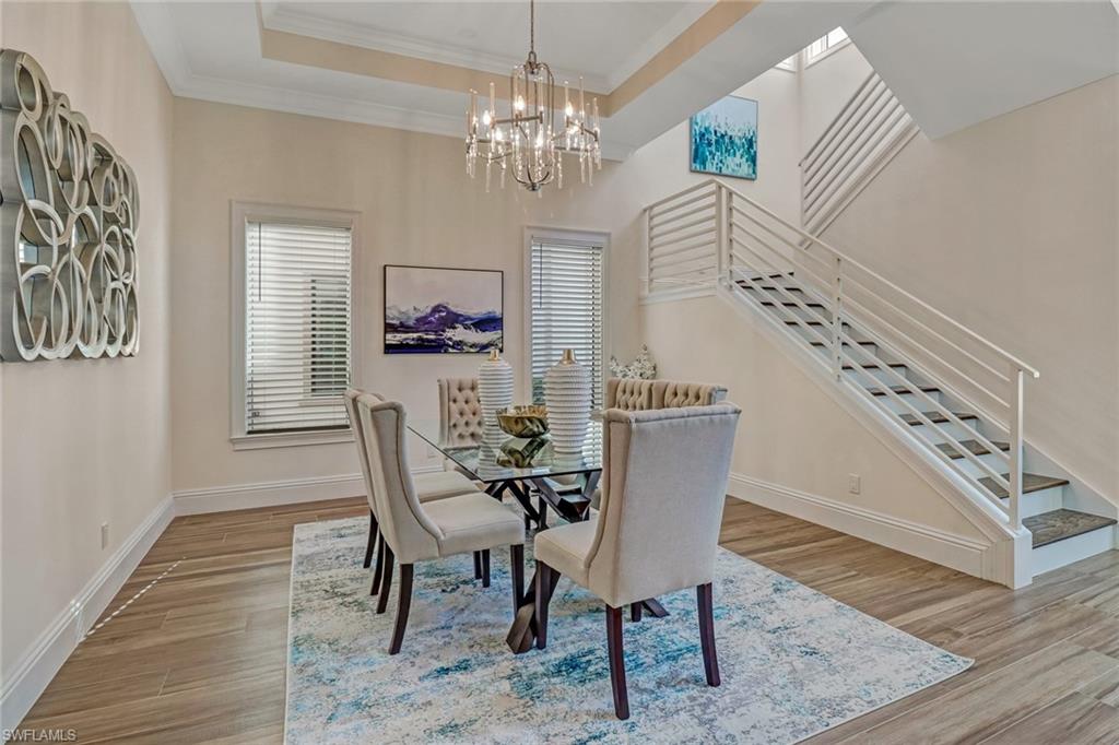 2875 Coco Lakes Drive Naples, FL 34105 - Photo 4 of 27 Dining space with a chandelier, light wood-type flooring, ornamental molding, and a tray ceiling