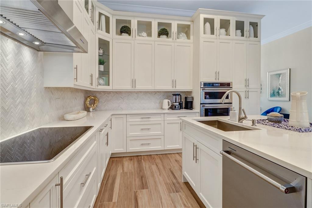 2875 Coco Lakes Drive Naples, FL 34105 - Photo 6 of 27 Kitchen featuring white cabinetry, sink, wall chimney range hood, and stainless steel appliances