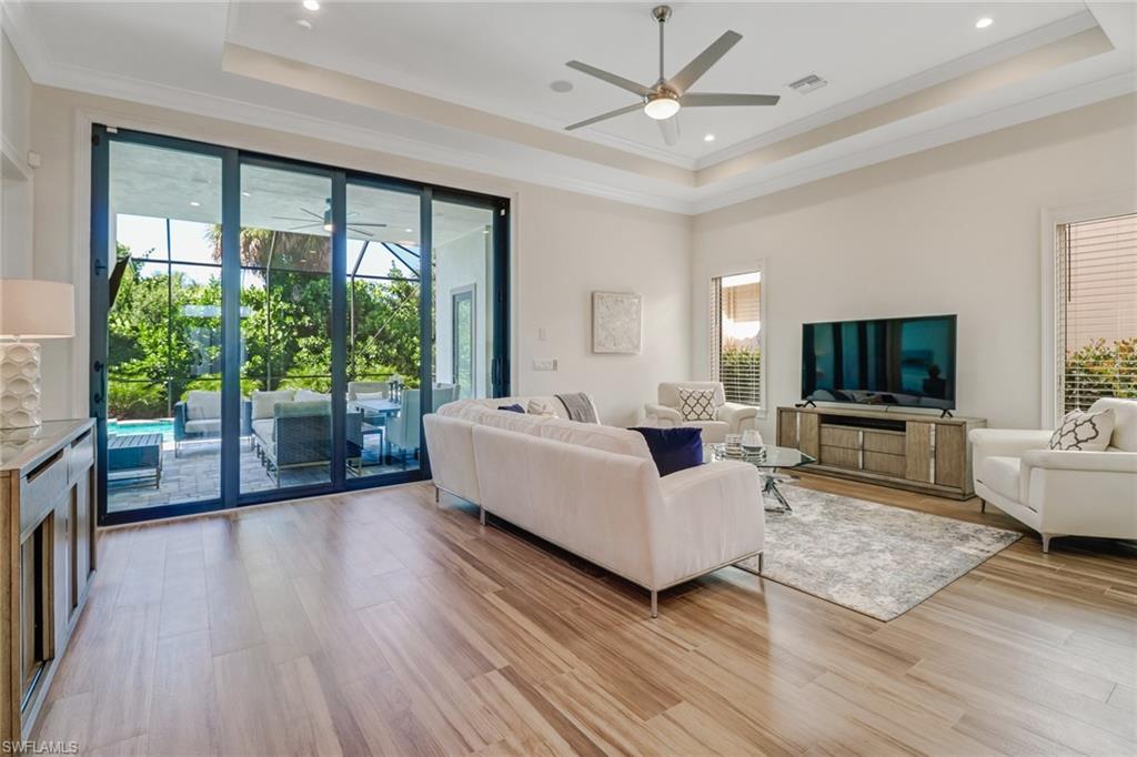 2875 Coco Lakes Drive Naples, FL 34105 - Photo 10 of 27 Living room with a tray ceiling, crown molding, and light hardwood / wood-style flooring