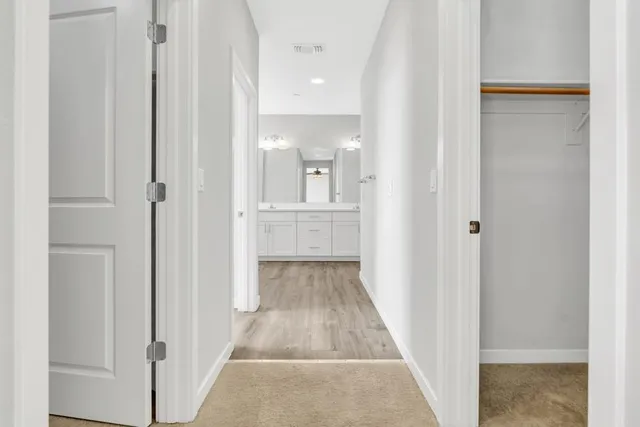 a view of a hallway with wooden floor and a bathroom