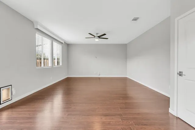 an empty room with wooden floor and windows