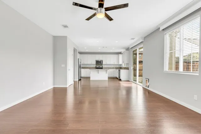 a view of empty room with wooden floor and windows