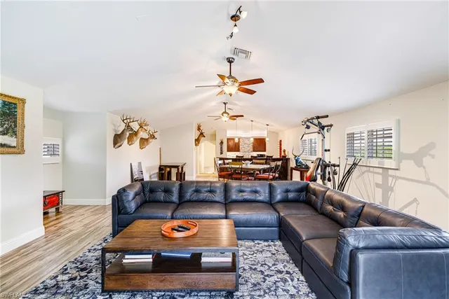 a living room with furniture kitchen view and a wooden floor