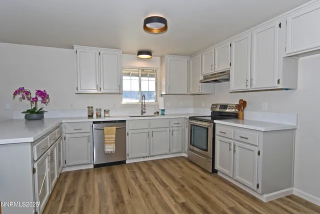 a kitchen with white cabinets white appliances sink and dishwasher with wooden floor