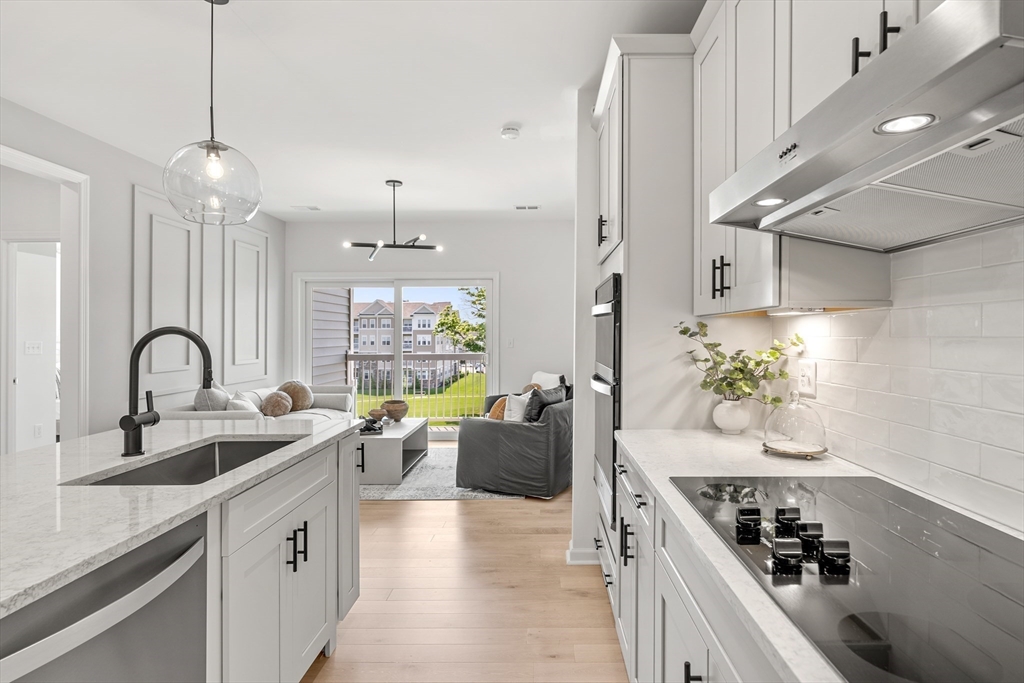 30 Coppersmith Way, Unit 409 Canton, MA 02021 - Photo 4 of 26 a kitchen with sink a stove and white cabinets with wooden floor
