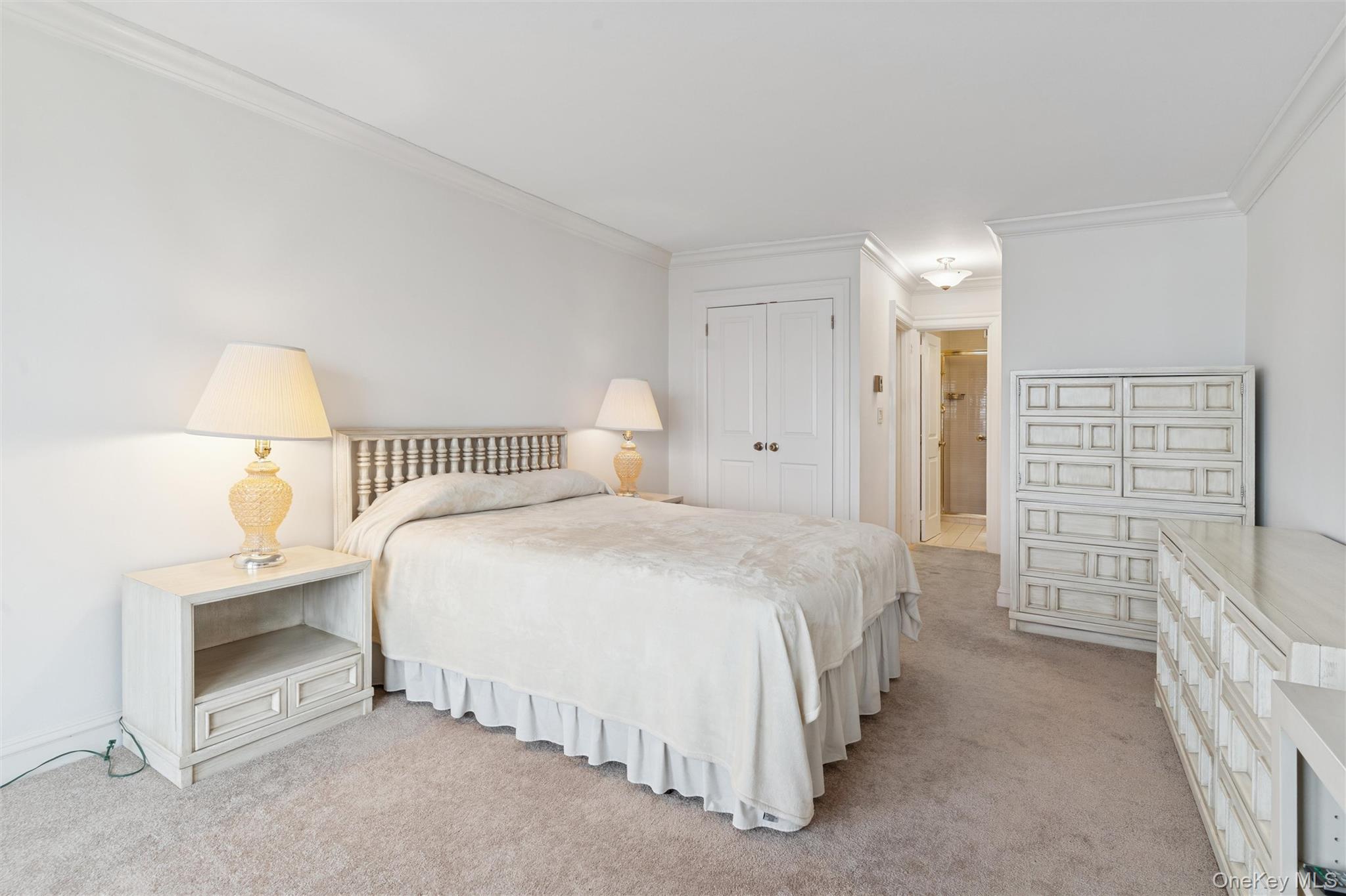 17-85 215th Street, Unit 15M Queens, NY 11360 - Photo 20 of 30 a spacious bedroom with a bed and a lamp