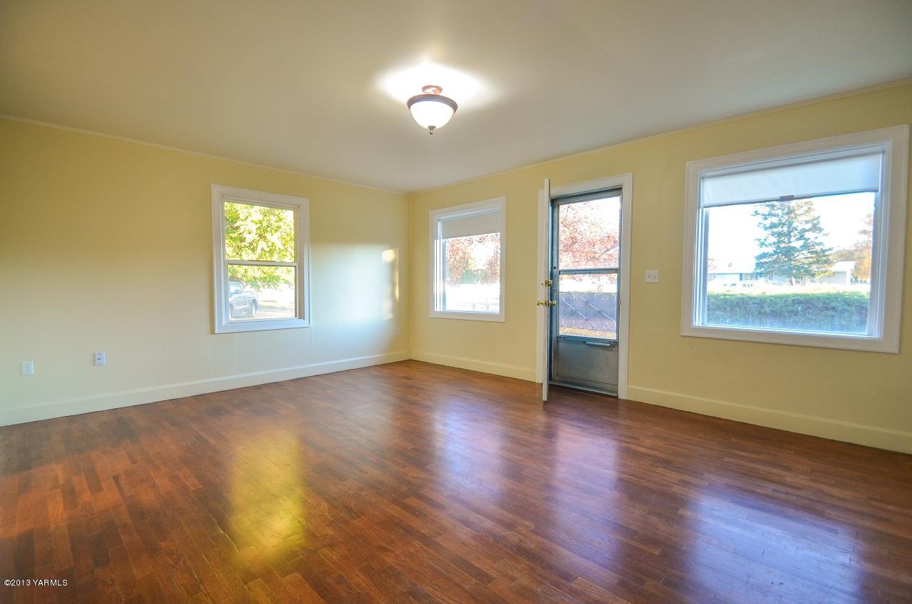 11703 Gilbert Road Yakima, WA 98903 - Photo 2 of 12 a view of an empty room with wooden floor and a window