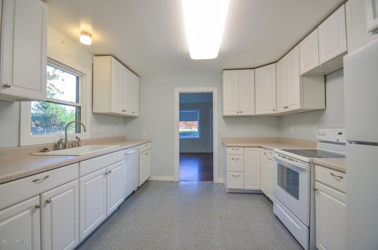 11703 Gilbert Road Yakima, WA 98903 - Photo 4 of 12 a kitchen with granite countertop white cabinets and white appliances