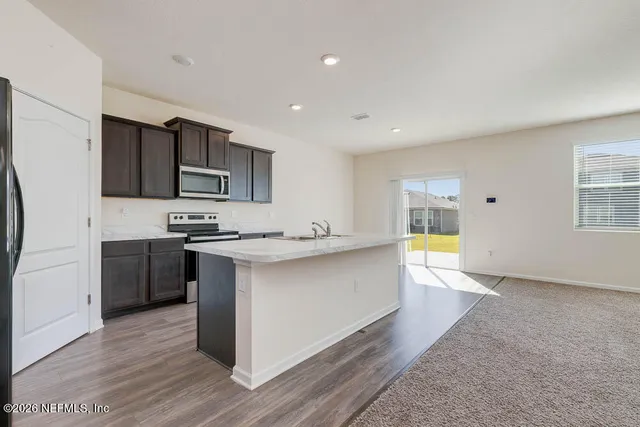 a large kitchen with a large counter top stainless steel appliances and cabinets