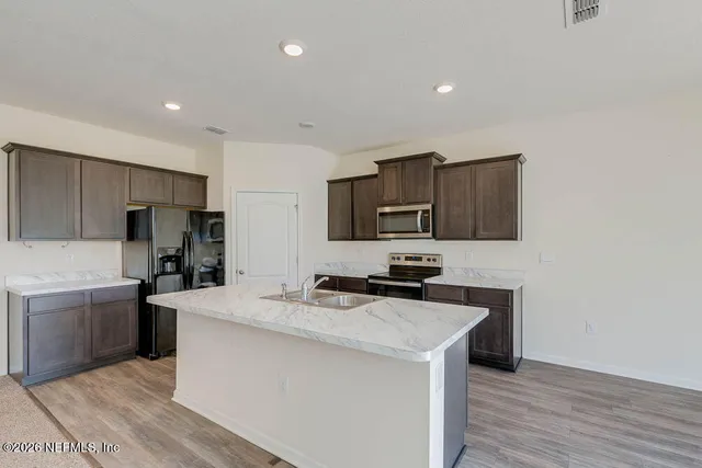 a kitchen with granite countertop a sink a counter top space stainless steel appliances and cabinets