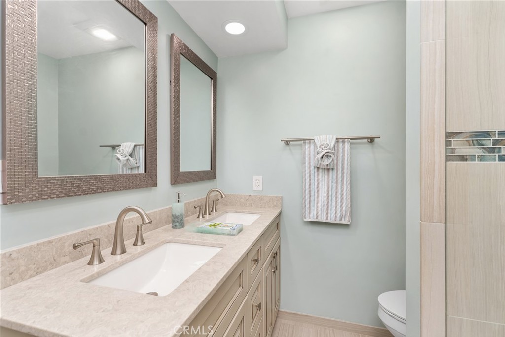 1837 North Studebaker Road Long Beach, CA 90815 - Photo 29 of 38 a bathroom with a granite countertop sink toilet and mirror