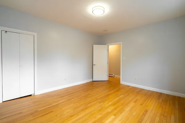 a view of an empty room with wooden floor and closet
