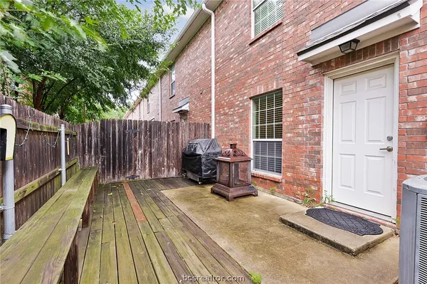 a view of backyard with brick wall and a table and chairs