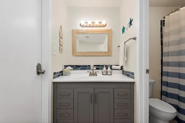 a bathroom with a granite countertop sink vanity mirror and toilet