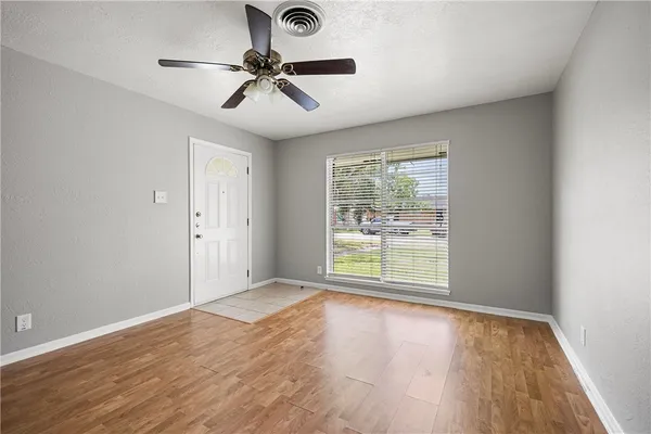 a view of an empty room with a window and wooden floor