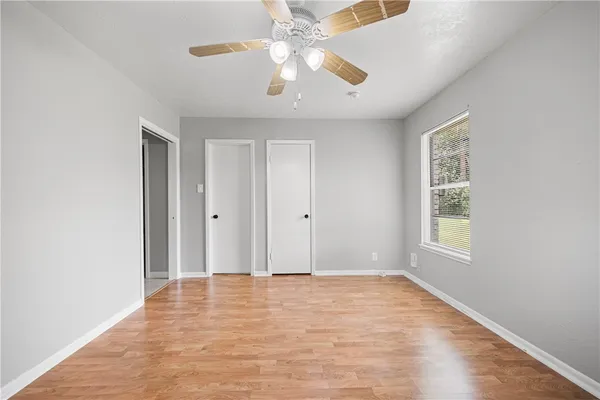 a view of an empty room with window and chandelier fan