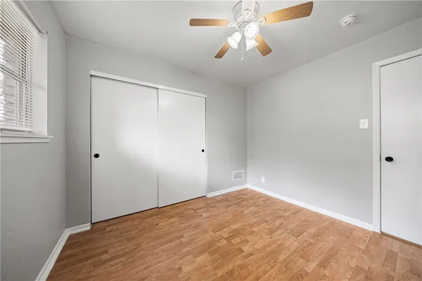 an empty room with windows and fan