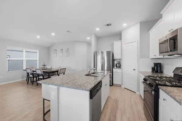a kitchen with stainless steel appliances granite countertop a sink a stove and a refrigerator