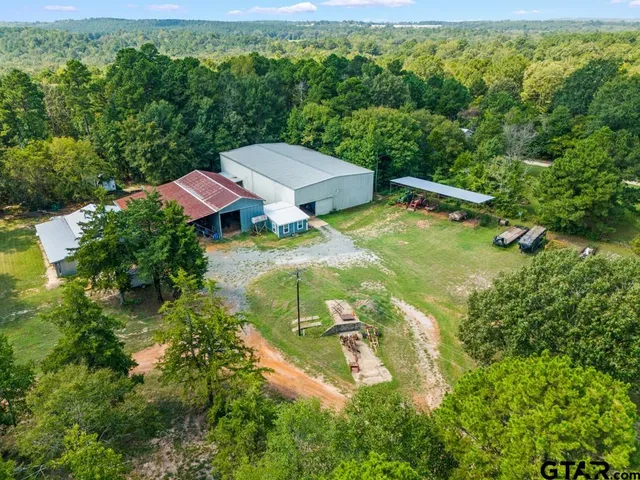 an aerial view of residential house with outdoor space and trees all around