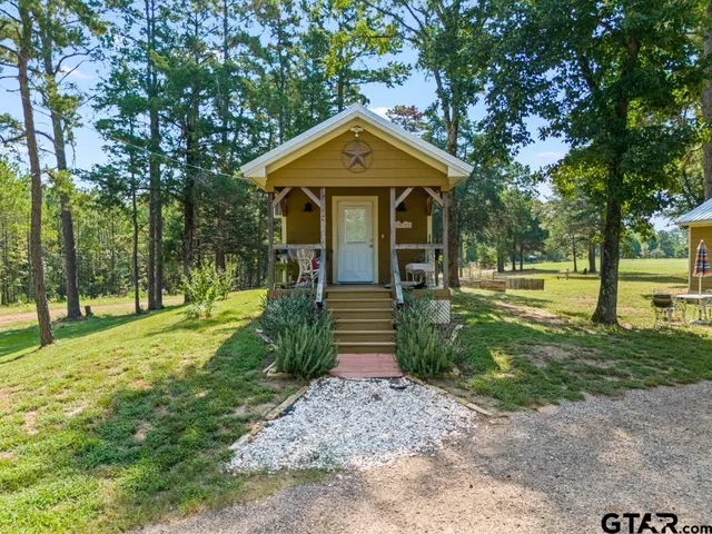 a front view of a house with garden and trees
