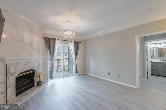 an empty room with wooden floor fireplace and windows