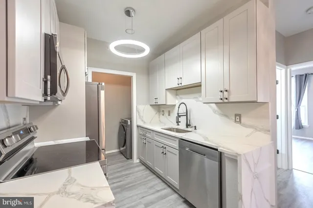 a kitchen with a sink dishwasher a refrigerator and white cabinets with wooden floor