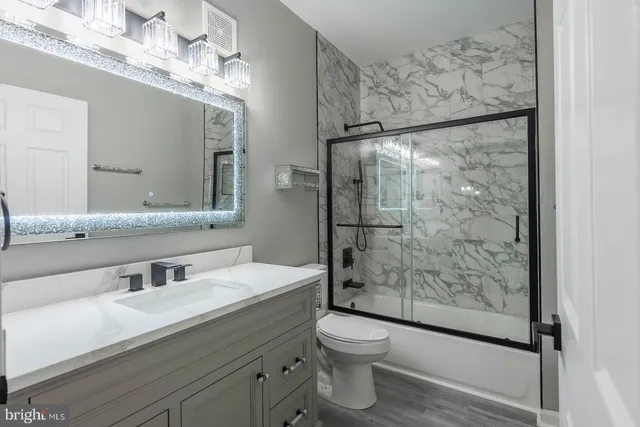 a bathroom with a granite countertop sink toilet and shower