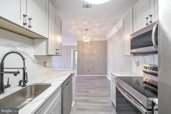 a kitchen with kitchen island granite countertop a sink stainless steel appliances and cabinets