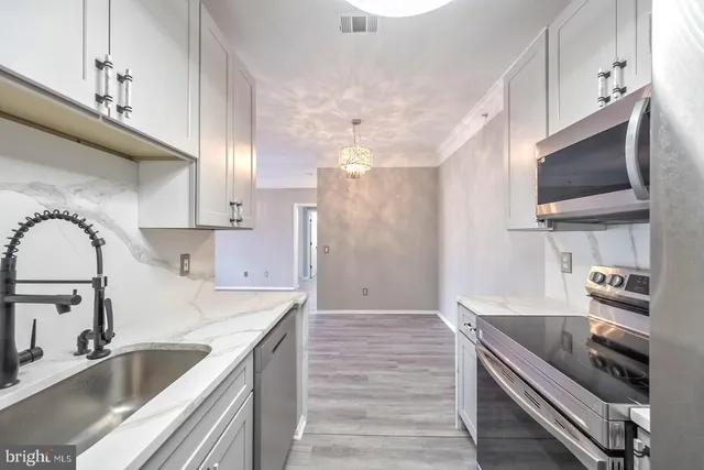 a kitchen with kitchen island granite countertop a sink stainless steel appliances and cabinets