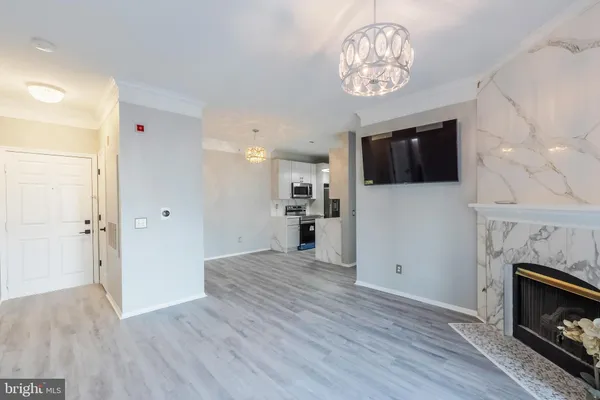 a view of a livingroom with a kitchen a fireplace a ceiling fan and windows