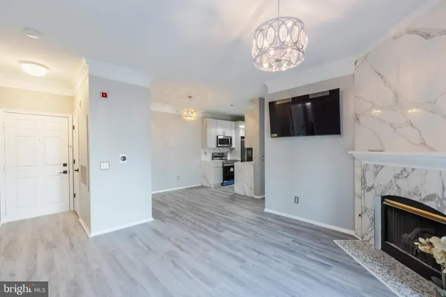 a view of a livingroom with a kitchen a fireplace a ceiling fan and windows