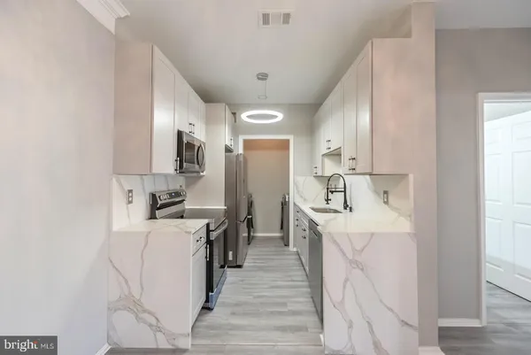 a kitchen with a sink a counter top space stainless steel appliances and cabinets