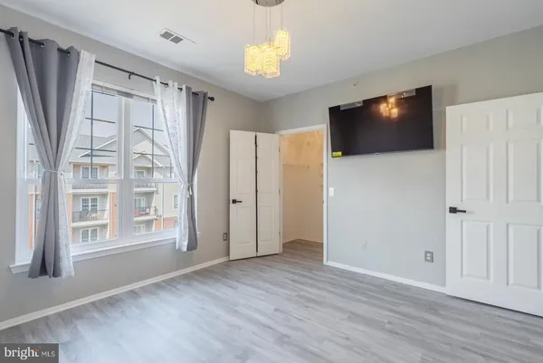 a view of an empty room with a window and wooden floor