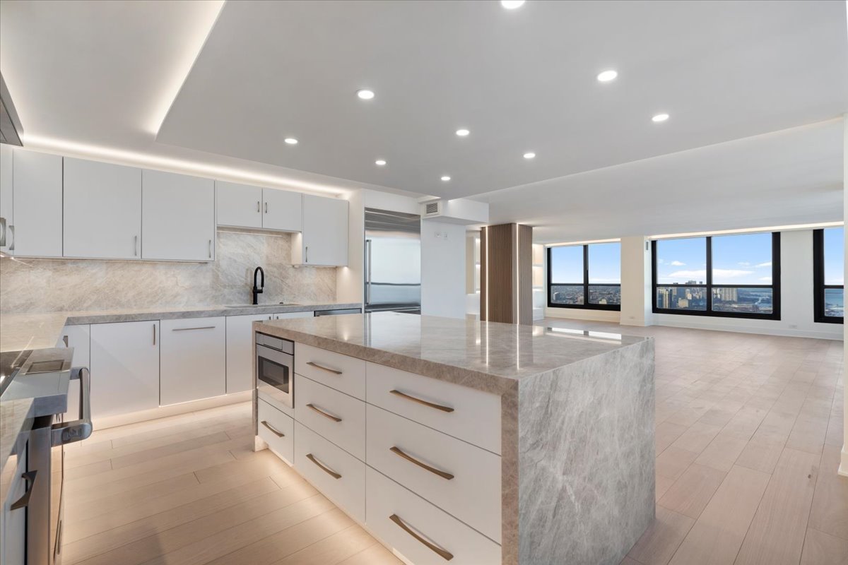 1030 North State Street, Unit 52EFG Chicago, IL 60610 - Photo 12 of 32 a kitchen with stainless steel appliances kitchen island granite countertop a stove a sink and a refrigerator with white cabinets