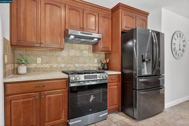 a kitchen with stainless steel appliances granite countertop a stove a refrigerator and a sink with cabinets