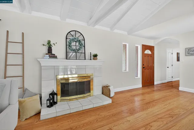 a view of an empty room with wooden floor and a fireplace