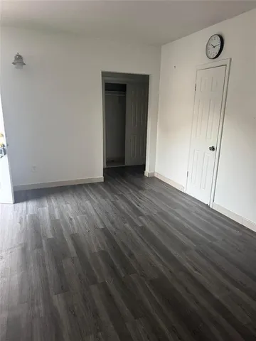 a view of an empty room with wooden floor and closet