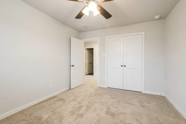an empty room with chandelier fan and closet