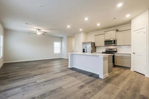 a kitchen with stainless steel appliances kitchen island granite countertop a stove a sink and a refrigerator