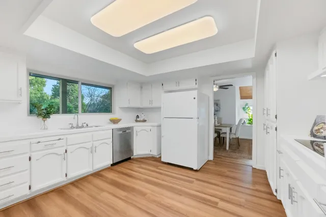 a kitchen with white cabinets and wooden floor
