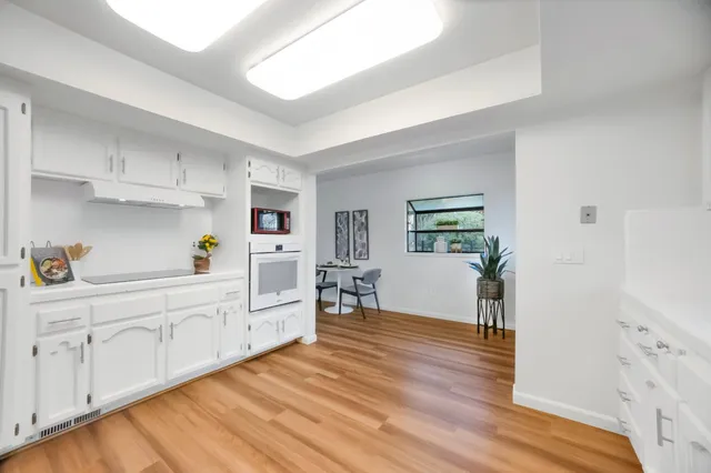a view of a kitchen with wooden floor and electronic appliances