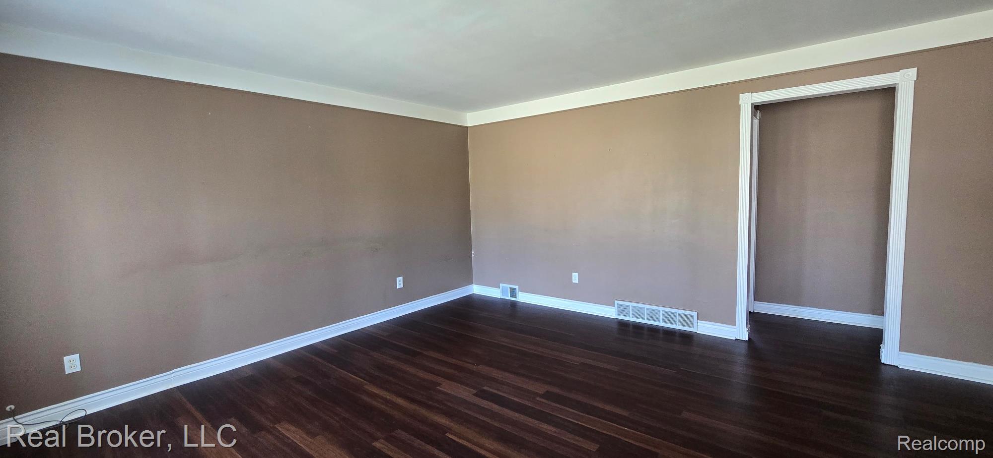 23401 Filmore Street Taylor, MI 48180 - Photo 8 of 16 Spacious room featuring dark wood-finish flooring, light tan walls, and crisp white baseboards and crown molding