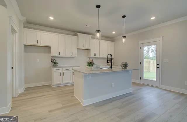 a kitchen with stainless steel appliances granite countertop a sink a stove a refrigerator and white cabinets with wooden floor