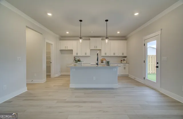 a view of kitchen with kitchen island white cabinets and stainless steel appliances